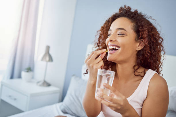Shot Of An Attractive Young Woman Taking Her Medication In Her Bedroom At Home